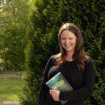photo of author megan michelle outside holding a copy of skylark